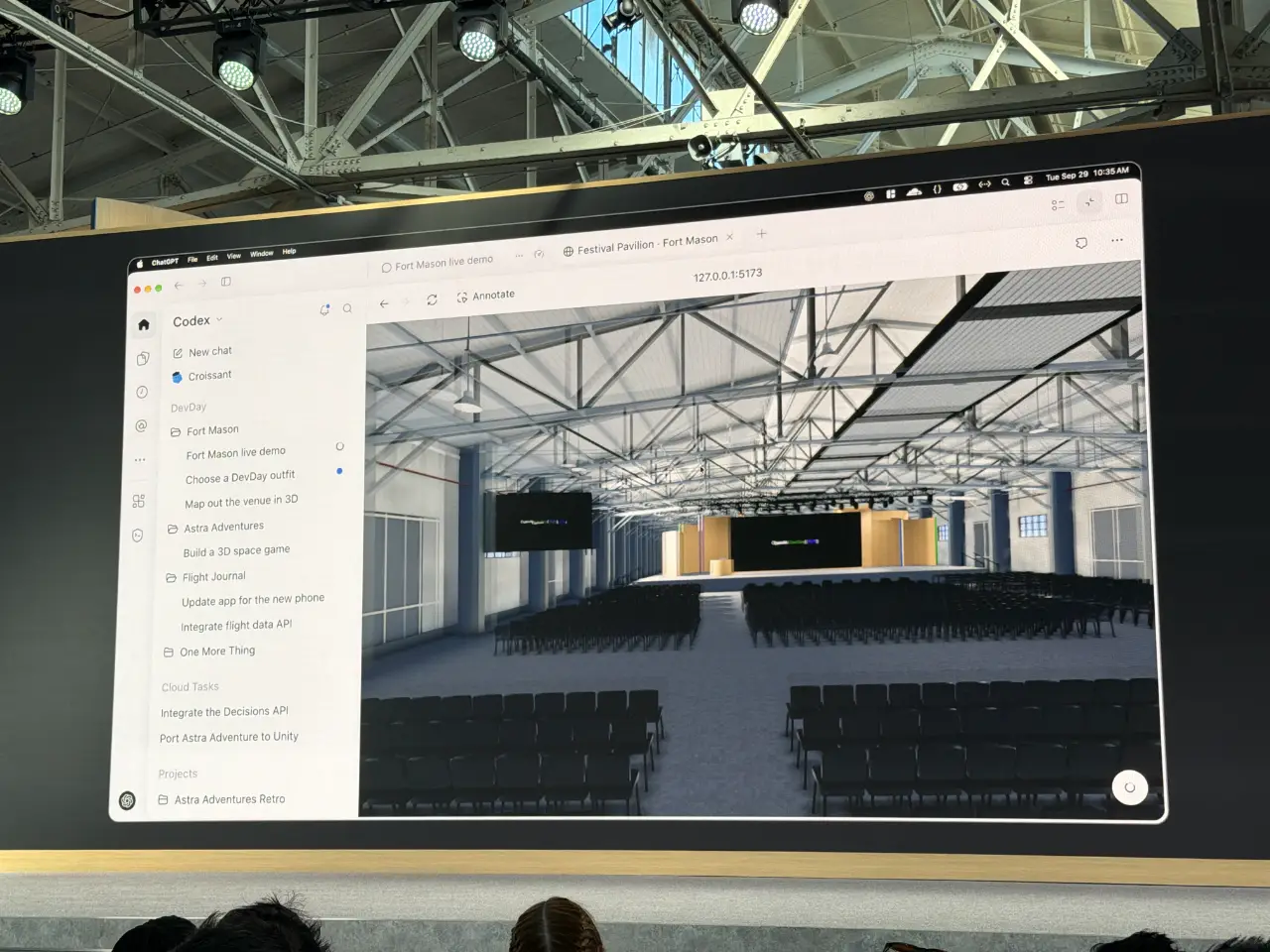 A large display at a tech event shows a computer-generated view of Fort Mason’s Festival Pavilion arranged for a conference, with rows of chairs facing a stage beneath exposed roof trusses. A Codex sidebar lists projects including “Fort Mason live demo” and “Map out the venue in 3D”; audience members’ heads are visible along the bottom.